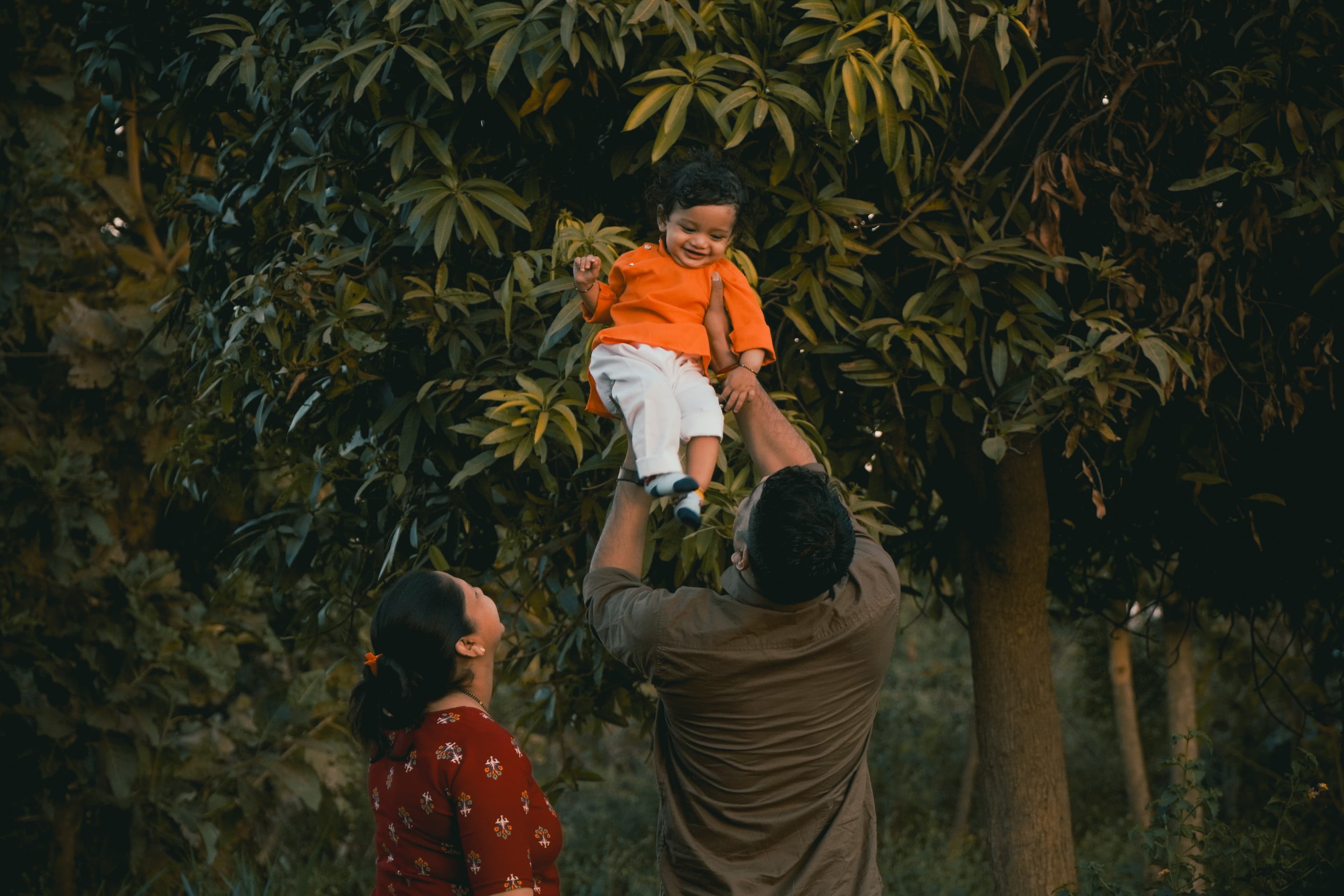 A father holds a young boy in his arms as the child's mother looks on