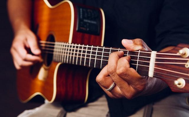 A guitar is being played, but all we can see are the musician's hands on the fretboard and strings.